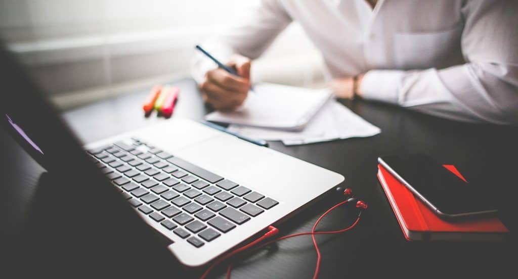 Person with pen, paper and laptop