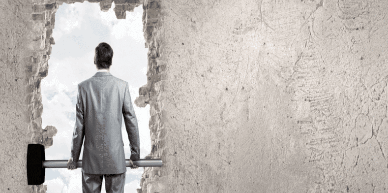 Man stands with oversize hammer next to hole in a wall