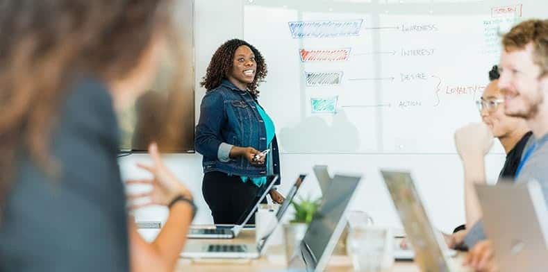 People smiling at business meeting in front of whiteboard