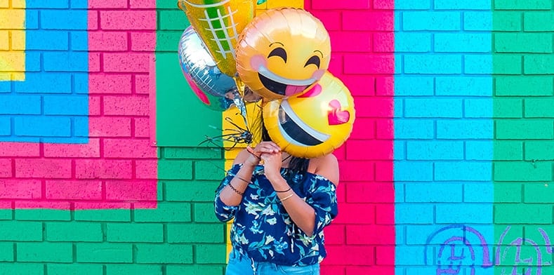 Person holding smiley face balloons