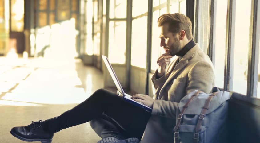 Man works on laptop in sunlight corridor