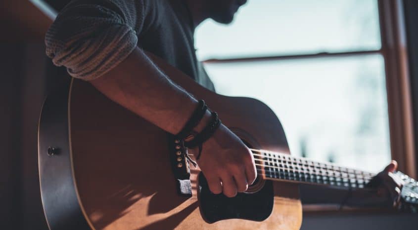 Person seated, playing and acoustic guitar