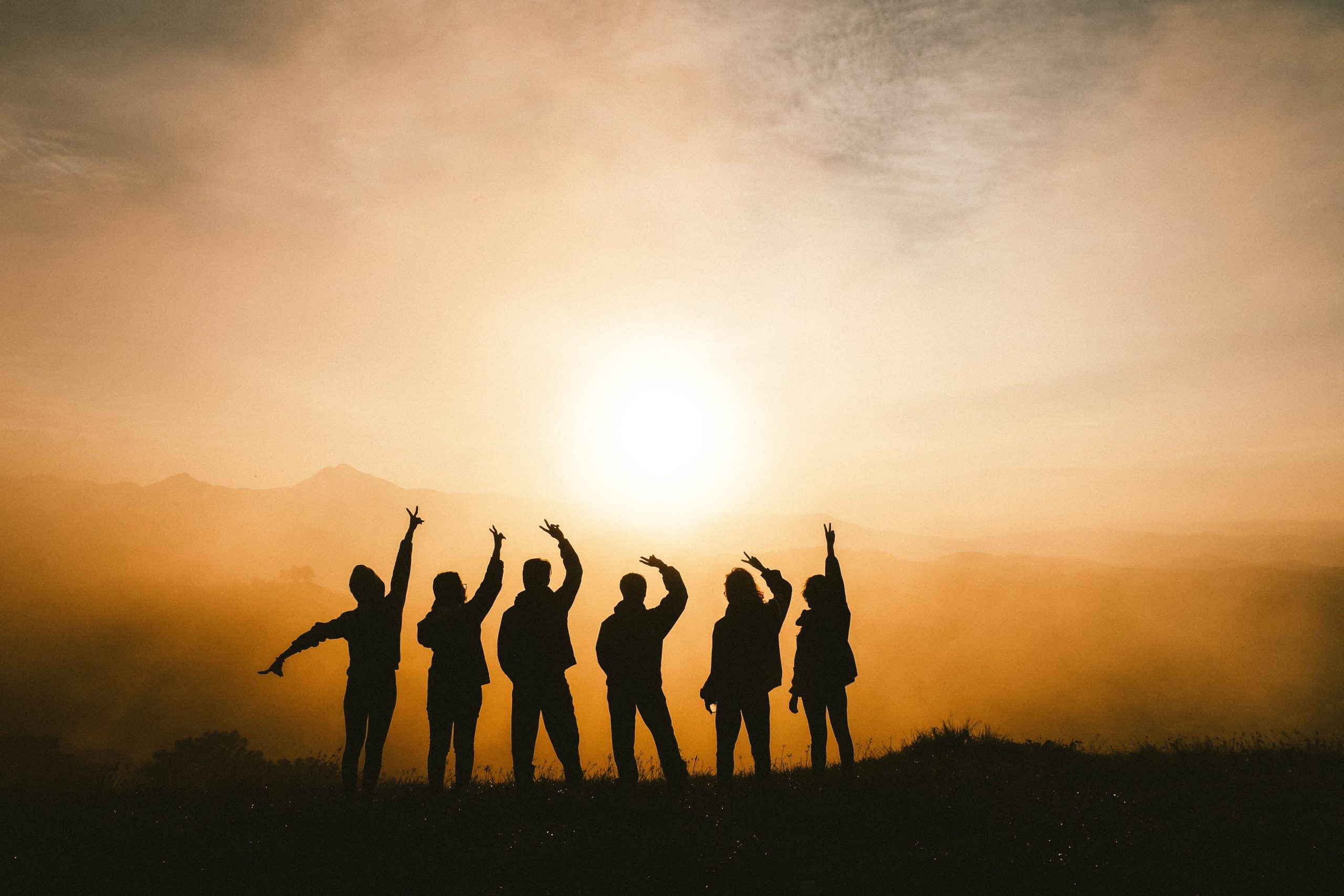 People on hilltop looking toward the sun