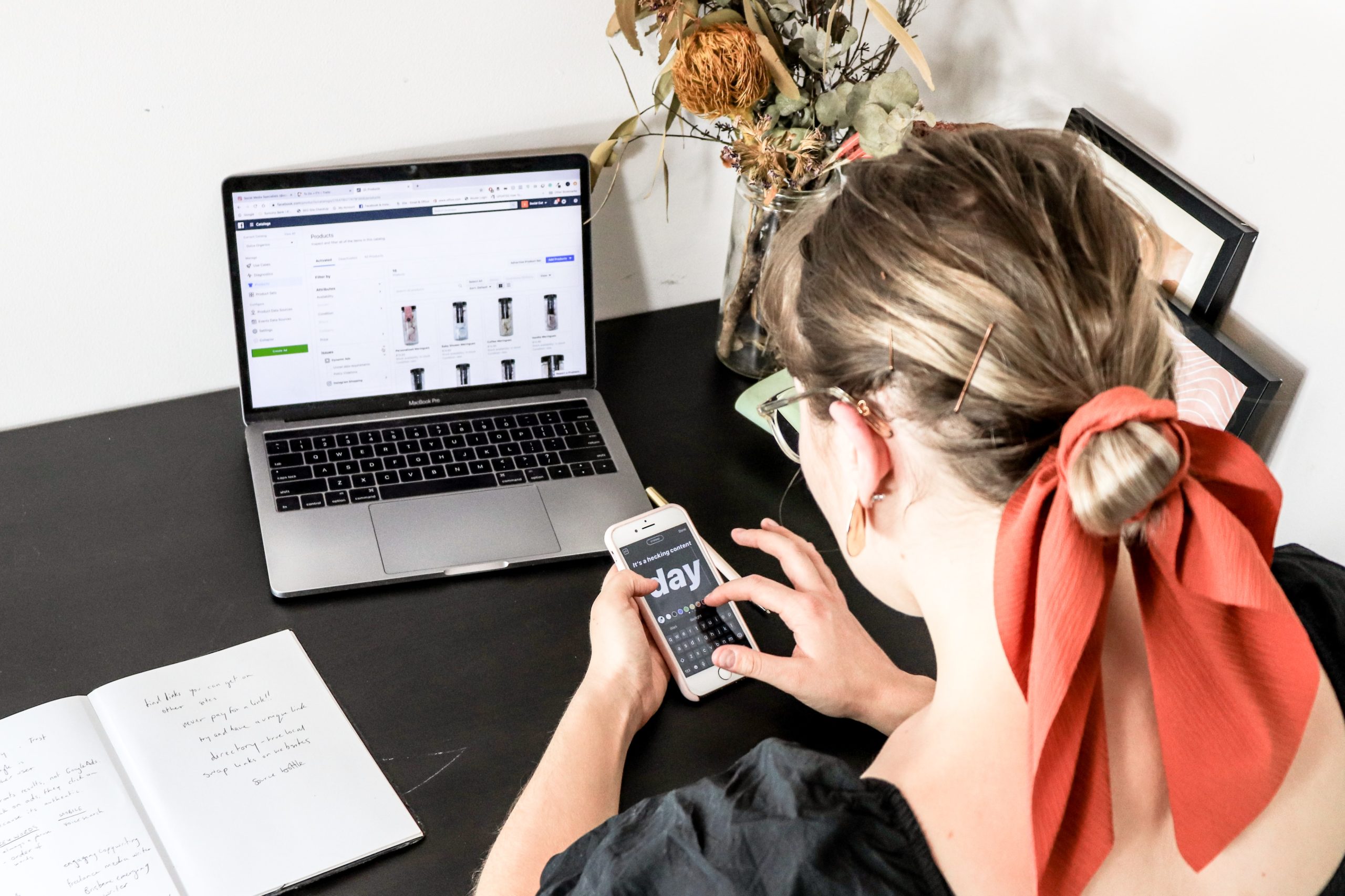 Person looks at mobile phone whislt sat in front of laptop