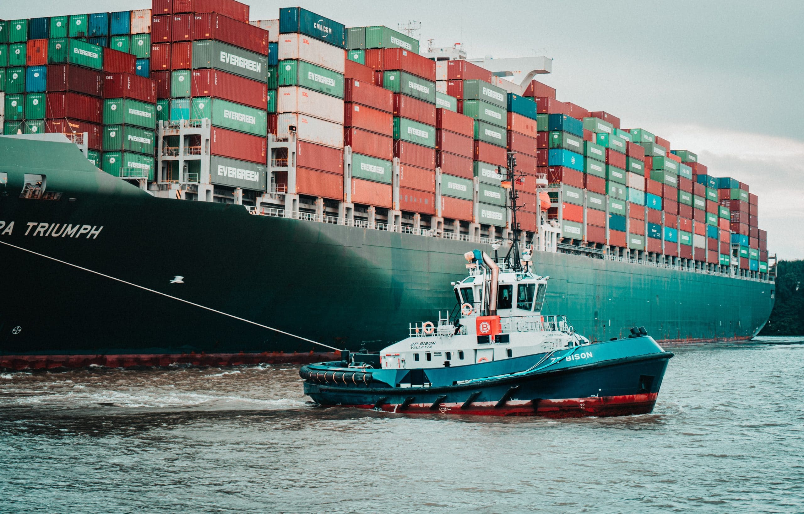 Tugboat pulling huge container ship