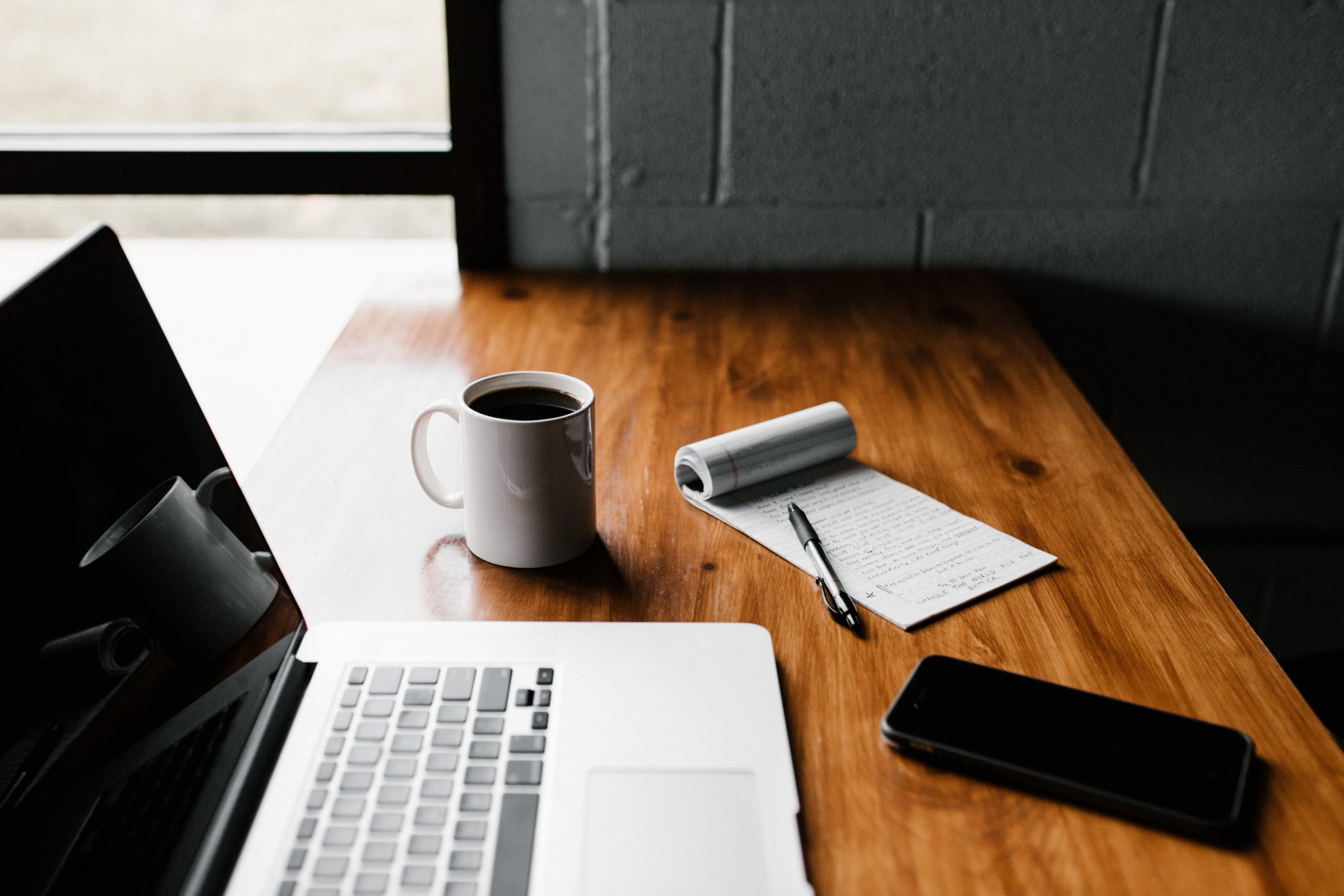 Desk with coffee, notebook, phone and laptop