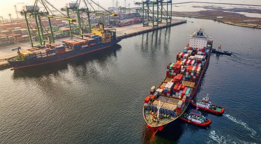 Container ship with tugboats in port