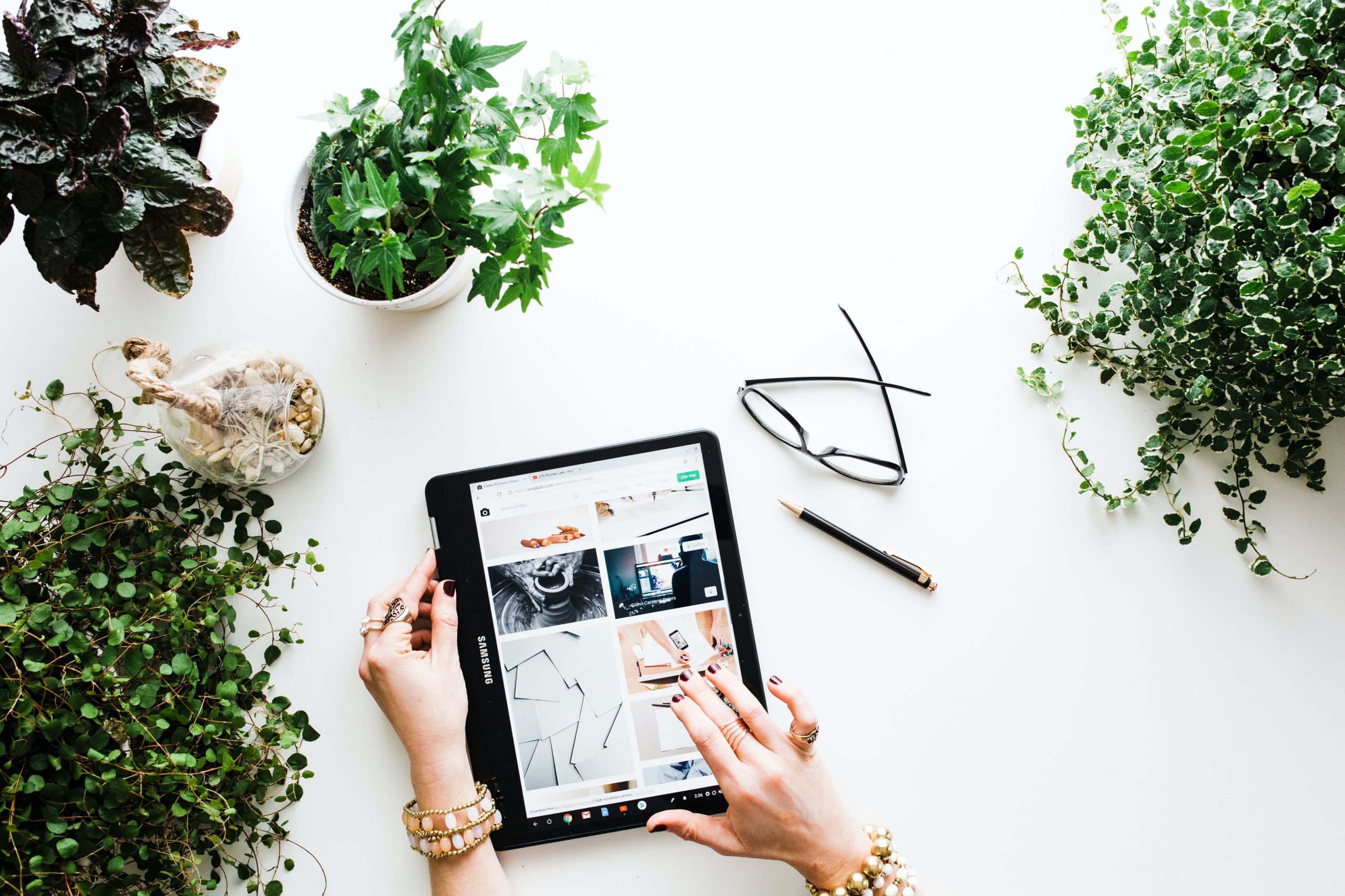 Top down shot of tablet on table surrounded by plants