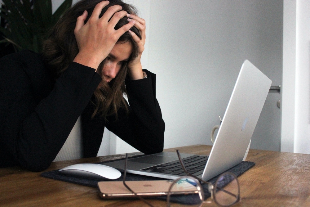 Person hold head in front of laptop