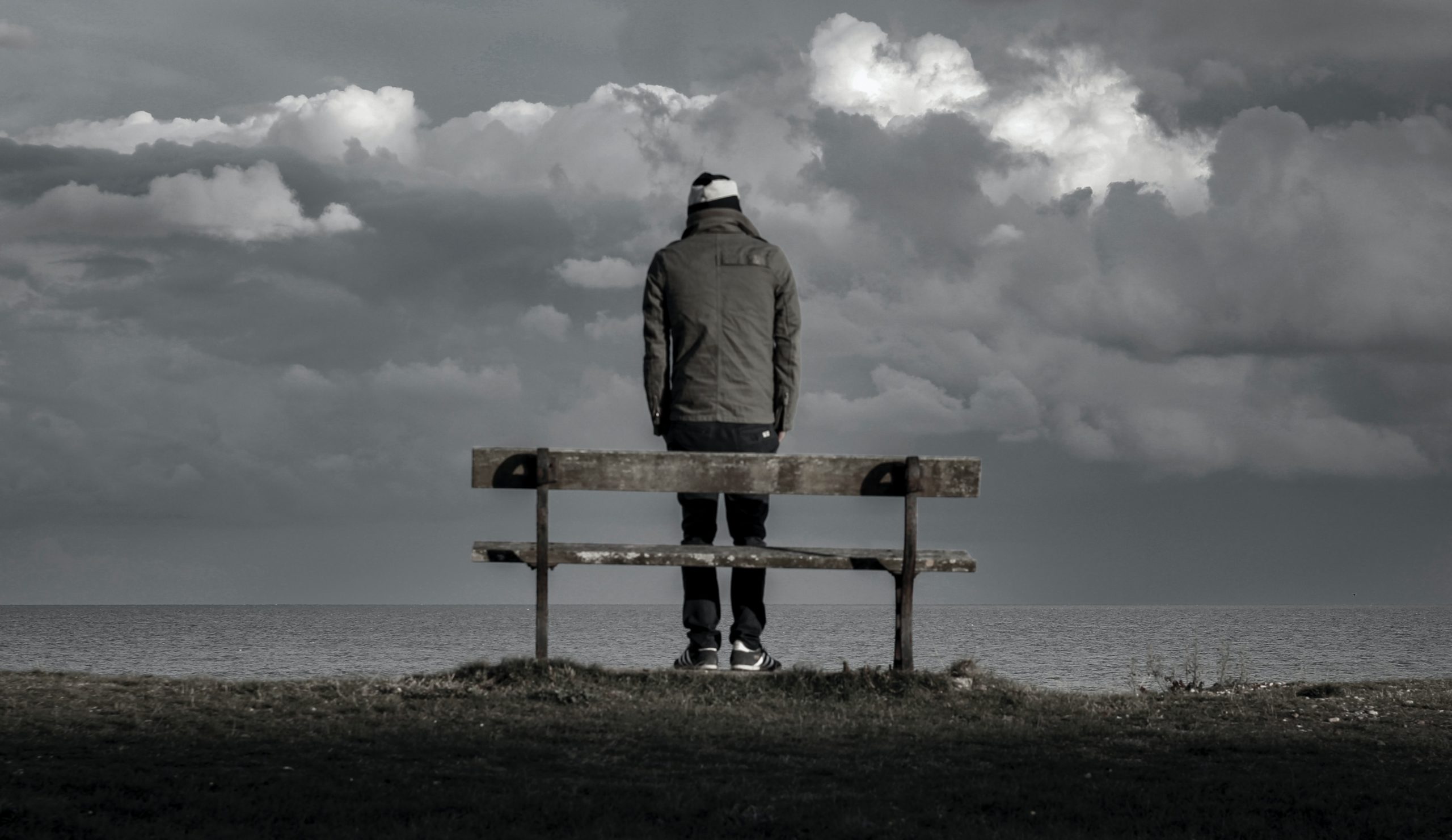 Person standing looking out to sea on cold grey day