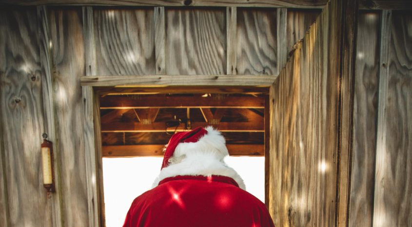 Person dressed as santa wlking down wooden hallway