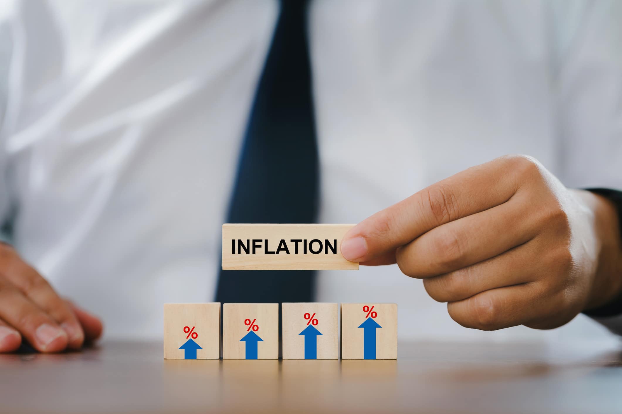 Businessman Hand holding a wooden block with the word inflation