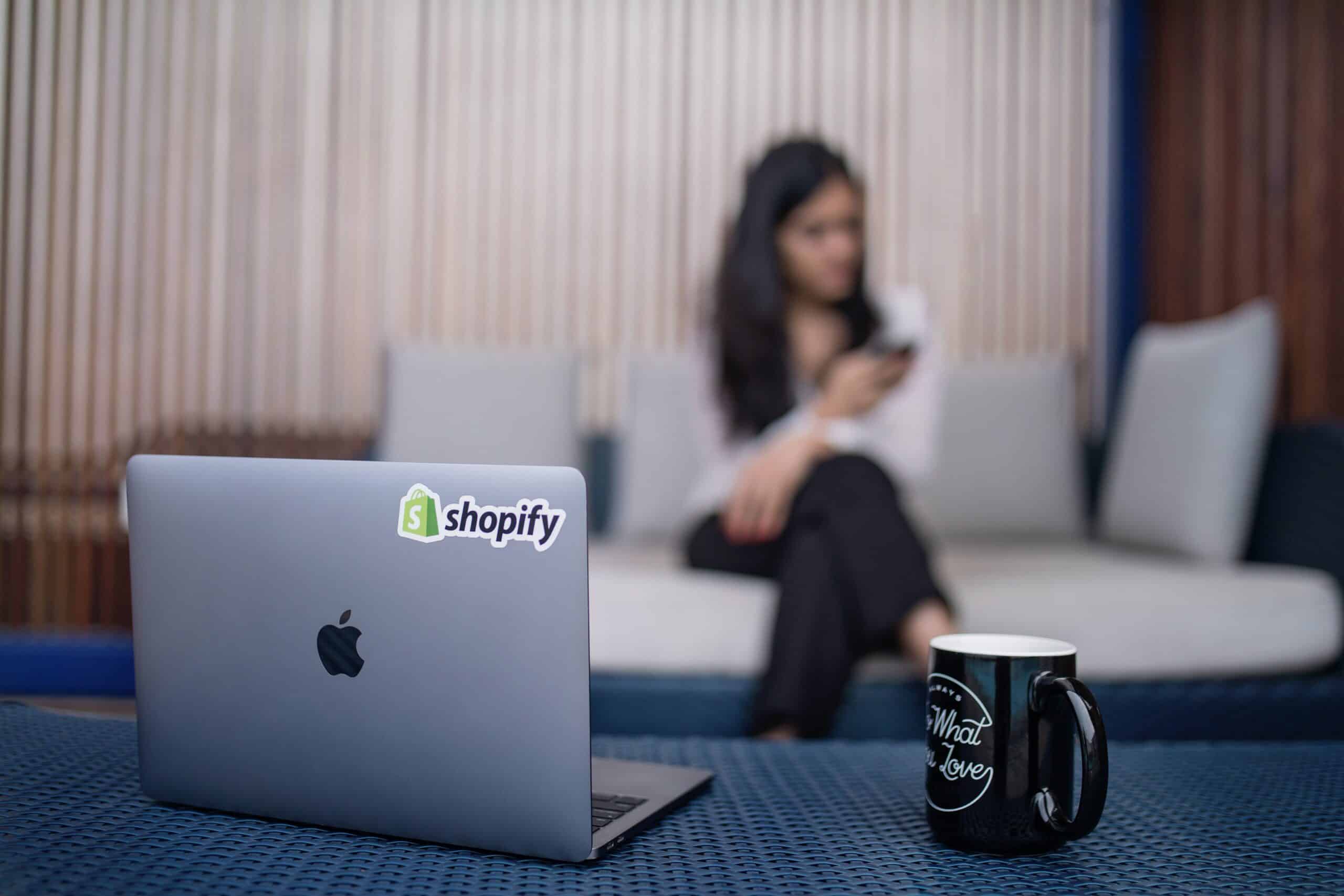 Laptop in foreground with shopify sticker