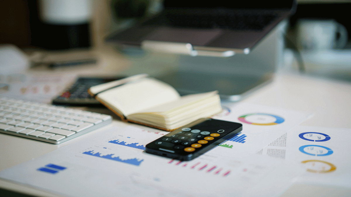 Financial reports with charts, a calculator, and a laptop on a desk, representing the analysis of non-operating expenses and business financial performance.
