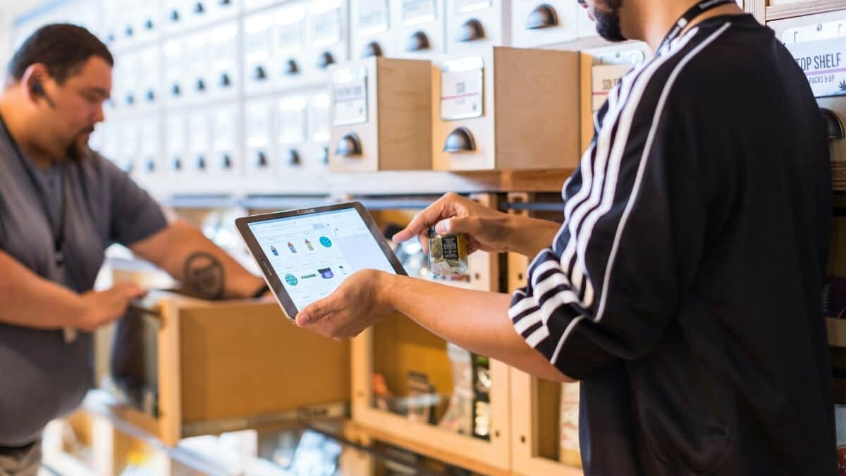 Retail staff using a digital tablet to manage omnichannel inventory and order fulfillment in-store.